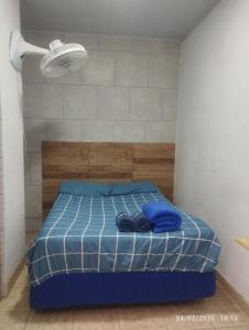 a bedroom with a bed with blue sheets and a light at Suíte 2 Itaguaí in Itaguaí