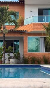 a house with a swimming pool in front of a building at Pousada Casa de Praia in Marechal Deodoro