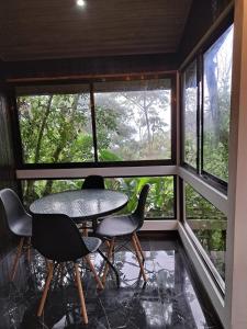 a table and chairs in a room with windows at Casa Tucan Glamping in Turrialba