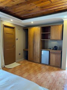 a room with a bed and a kitchen with wooden cabinets at Capri Hills in Mwanza