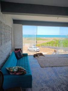 a blue couch in a living room with a cat laying on the floor at Casa da barra in Canguaretama