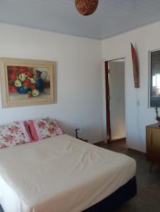 a bedroom with a white bed with a painting on the wall at Casa da barra in Canguaretama