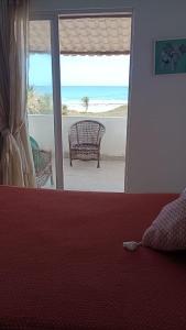 a bedroom with a view of the beach and a couch at Casa da barra in Canguaretama +5 photos