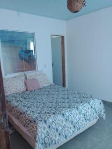 a bedroom with a bed with a blue and white comforter at Casa da barra in Canguaretama