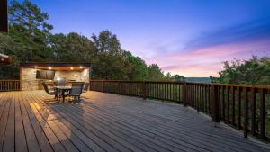 a wooden deck with a table and chairs on it at New Unbelievable Views Gourmet Kitchen Firepit in Broken Bow