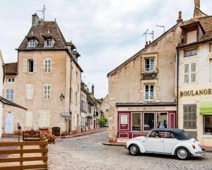 a white car parked in a street with buildings at Chez Barbara in Beaune