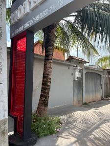 a building with a red sign next to a palm tree at Hotel ph in Barcarena