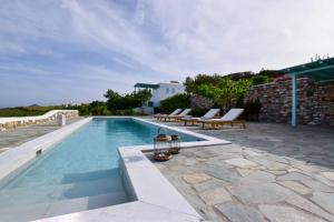 a swimming pool with lounge chairs next to a house at Aegean Queen Villas - Onar Hotels Collection in Naousa