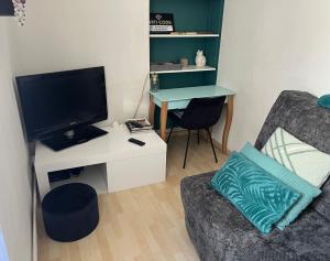 a living room with a couch and a desk with a television at Chez Barbara in Beaune