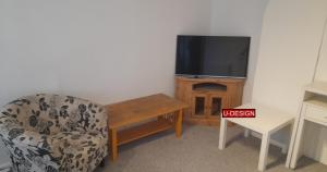 a living room with a chair and a television at The Green Yard - Ebike Available for Guests in Sundon