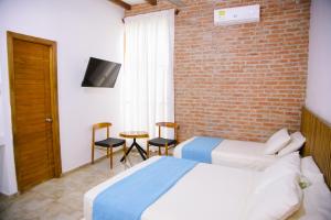 a bedroom with two beds and a brick wall at Hotel Palmas del Río Mompox in Mompos