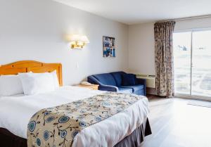 a hotel room with a bed and a blue chair at Mon Joli Motel in Sainte-Flavie