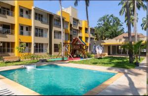 a swimming pool in front of a building with a playground at Charvi Reemz Anjuna in Anjuna
