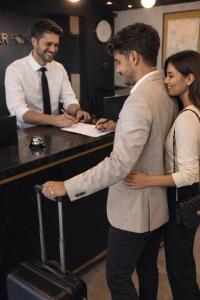 two men and a woman standing in front of a counter at Hotel Interforum in León