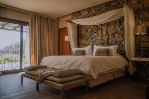 a bedroom with a large bed with a stone wall at Awasi Mendoza in Ciudad Lujan de Cuyo