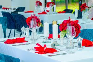 a table with white tables with red flowers and candles at Olifile Boutique Hotel & Restaurant in Midrand