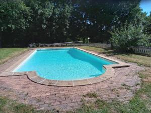 a swimming pool in a yard with a brick walkway around it at Chez Wan'Elle in Thorigné-sur-Dué