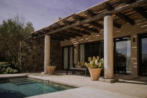 a house with a swimming pool and a wooden pergola at Awasi Mendoza in Ciudad Lujan de Cuyo
