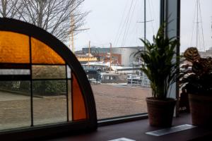 a window with a potted plant and a view of a marina at BBgebouw39 - op de Rijkswerf in Den Helder