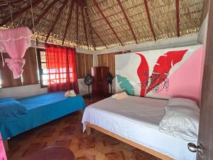 a bedroom with two beds and a straw roof at Terra Tipi in Guayabas