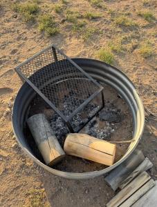 a grill with fire and some logs and wood at Base Camp Ranch House in Alamosa