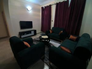 a living room with couches and a flat screen tv at Ark House in Soroti