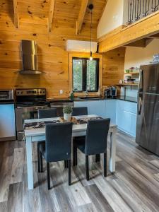 a kitchen with a table and chairs and a refrigerator at Chalet cozy en bord de lac in Saguenay
