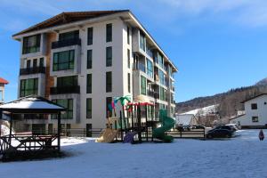 a apartment building with a playground in the snow at Hotel Bobline 304 in Bakuriani