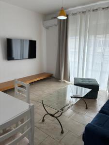 a living room with a glass coffee table and a tv at Bejart Apartment 8 in Tirana