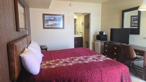 a hotel room with a red bed and a desk at Classic Inn Lancaster in Lancaster