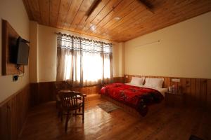 a bedroom with a bed and a window and a chair at Village Crown in Mundaghat 