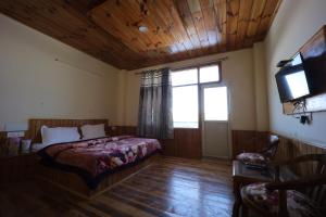 a bedroom with a bed and a television in it at Village Crown in Mundaghat 