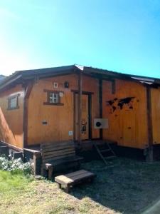 a wooden cabin with a bench and a house at Casa Montanara in El Chalten