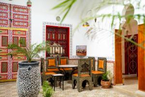 a room with a table and chairs and a red door at Riad Dar Mima Hnina - 2 Pools, Breakfast, 10' From Jamaa el-Fna, 10' From Airport in Marrakesh