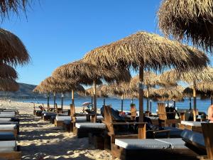 a row of chairs and straw umbrellas on a beach at AsproLux Seaside Studios in Asprovalta