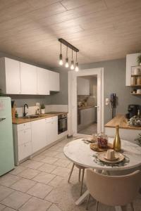 a kitchen with a table and a kitchen with white cabinets at La maison des Oiseaux in Martelange