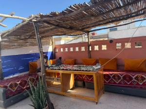a patio with a table and chairs under a roof at Dar Laila Surf in Tamraght Ouzdar