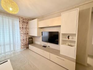 a living room with a flat screen tv and white cabinets at FLH - Obralix Home in Sibiu +42 photos