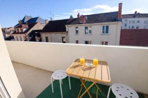 a table on a balcony with two glasses of orange juice at Le Kuku Beach - Appartement de charme à Digoin in Digoin
