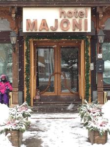Una donna in piedi di fronte alla porta di un hotel nella neve di Hotel Majoni a Cortina dʼAmpezzo