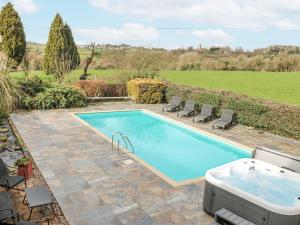 a swimming pool with chairs and a bath tub at Woodpit Cottage in Nottingham