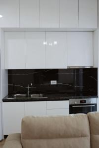a kitchen with white cabinets and a couch at Shehu Apartments in Tirana +67 photos