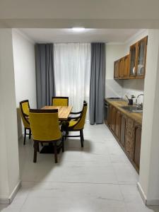 a kitchen with a wooden table and yellow chairs at Bejart Apartment 9 in Tirana +10 photos