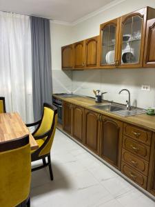 a kitchen with wooden cabinets and a sink and a table at Bejart Apartment 9 in Tirana