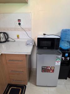 a microwave on top of a refrigerator in a kitchen at Alyahomes in Nairobi +4 photos