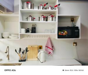 a kitchen with white shelves with pots and pans at Marine waters retreat Block A in Embu