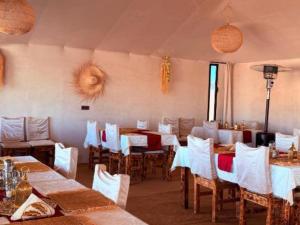 a dining room with tables and chairs with white tables and white chairs at Dream Land Camp in Merzouga +22 photos