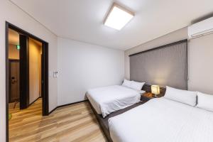 two beds in a hotel room with a window at Hakone Mori No Sato 箱根森の郷 in Sekishoato