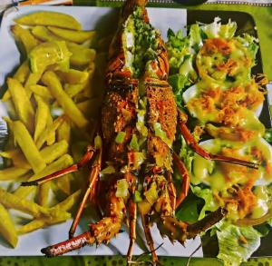 a plate of food with a lobster and french fries at NaturUbuntu in Kafountine