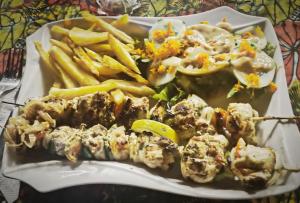a plate of food with french fries on a table at NaturUbuntu in Kafountine +64 photos